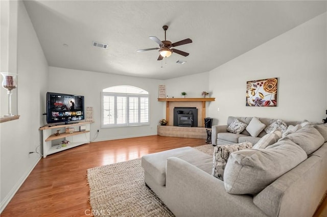 living room with wood finished floors, visible vents, baseboards, vaulted ceiling, and a ceiling fan