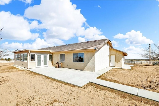 rear view of property with french doors, a patio area, fence, and stucco siding