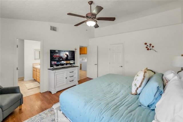 bedroom featuring lofted ceiling, ceiling fan, light wood-style flooring, visible vents, and ensuite bath