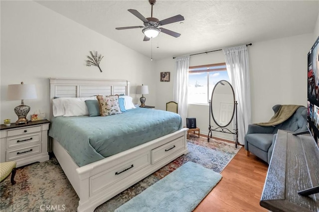 bedroom with lofted ceiling, light wood-style flooring, and a ceiling fan