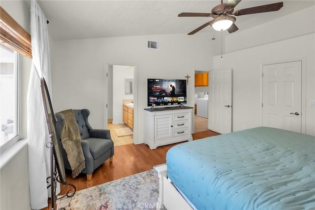 bedroom with lofted ceiling, connected bathroom, visible vents, a ceiling fan, and light wood-type flooring