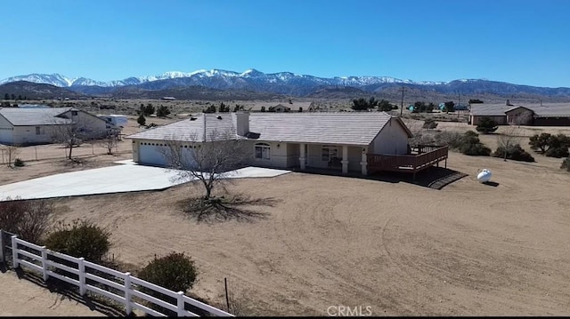 exterior space featuring concrete driveway, fence, a deck with mountain view, and an attached garage