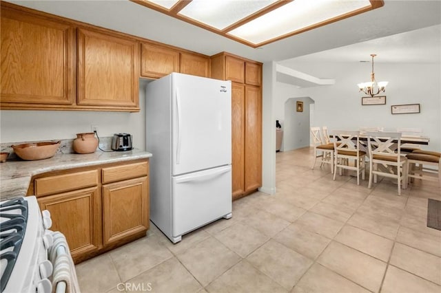 kitchen featuring white appliances, light tile patterned floors, arched walkways, brown cabinets, and light countertops