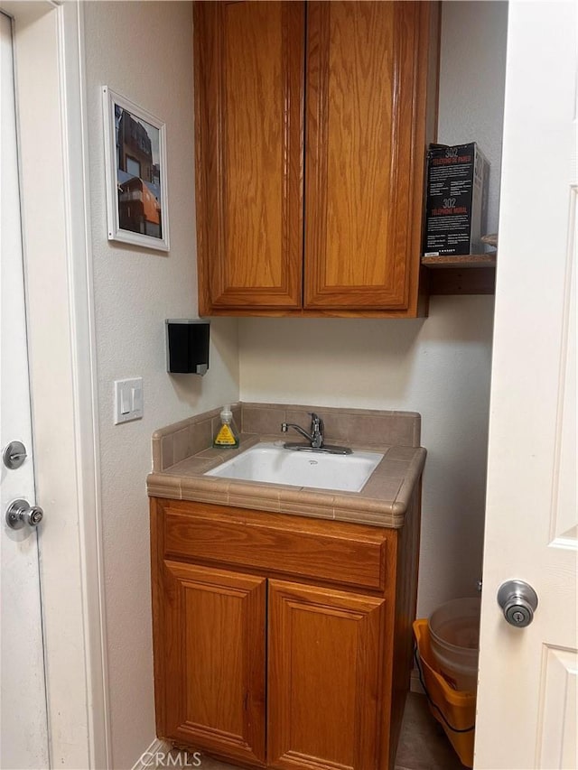 kitchen with a sink, tile counters, and brown cabinets