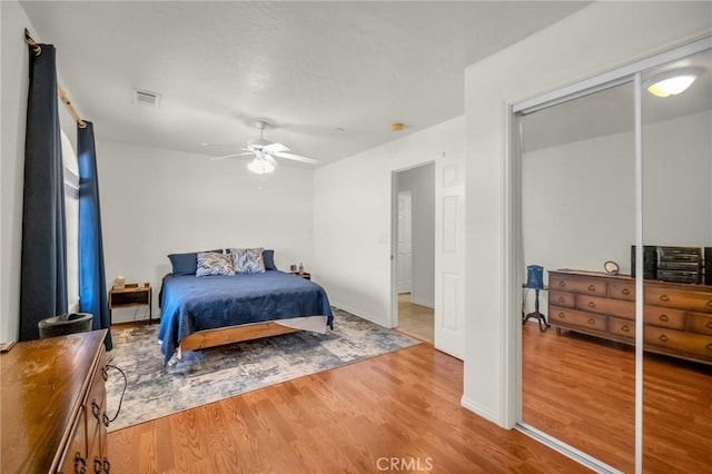 bedroom featuring a ceiling fan, a closet, visible vents, and wood finished floors