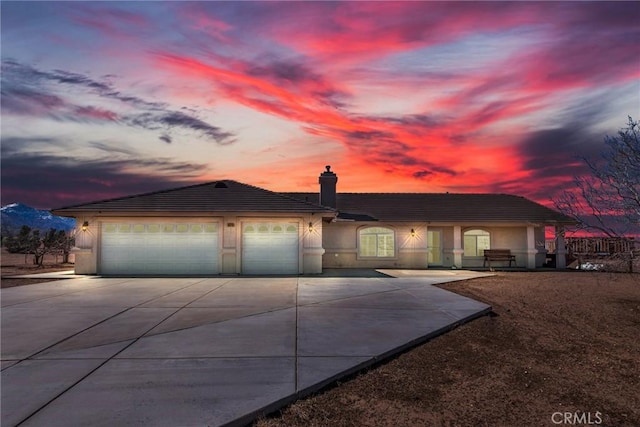 ranch-style home with a garage, concrete driveway, a chimney, and stucco siding