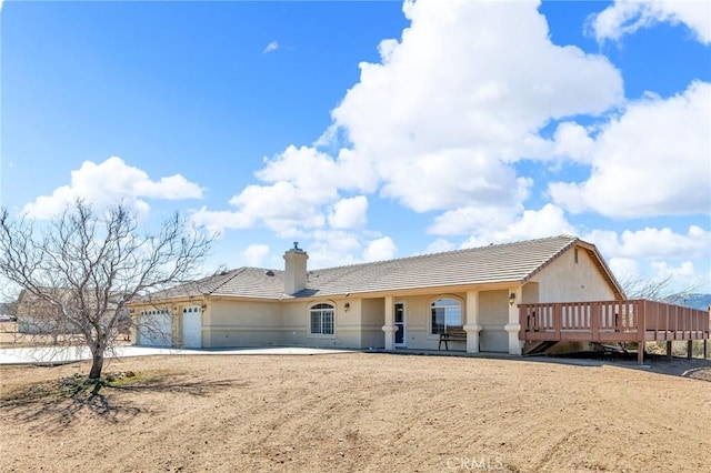 ranch-style house with a tiled roof, a chimney, an attached garage, and stucco siding