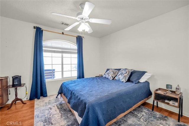 bedroom featuring baseboards, wood finished floors, visible vents, and a ceiling fan