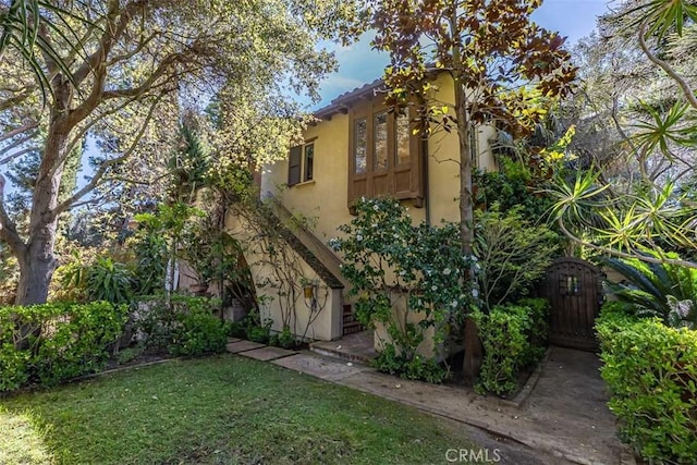 view of front of property featuring stucco siding, a gate, and a front yard