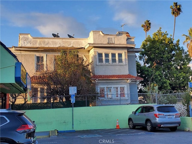 view of front of property with uncovered parking, a fenced front yard, and stucco siding