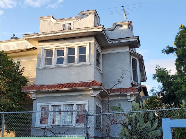 view of side of home with fence and stucco siding