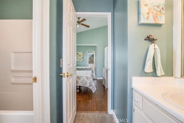 ensuite bathroom featuring baseboards, a ceiling fan, lofted ceiling, ensuite bath, and vanity