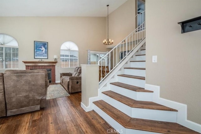 foyer entrance with baseboards, hardwood / wood-style flooring, stairway, a fireplace, and a notable chandelier