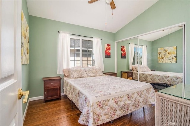 bedroom with baseboards, a ceiling fan, dark wood-type flooring, vaulted ceiling, and a closet