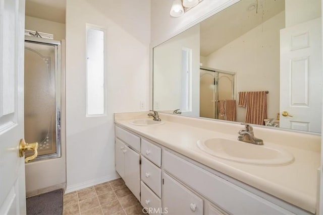 bathroom featuring a shower with door, a sink, baseboards, and double vanity