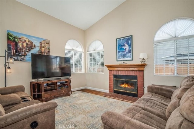 living area with lofted ceiling, a brick fireplace, baseboards, and wood finished floors