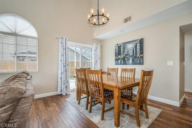 dining area with baseboards, visible vents, a chandelier, and wood finished floors