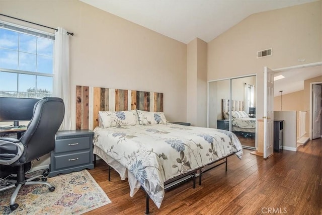 bedroom with high vaulted ceiling, a closet, visible vents, and dark wood-style flooring