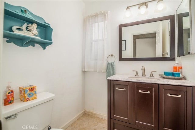 half bathroom with toilet, baseboards, and vanity