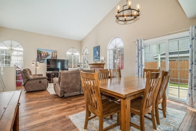 dining room with high vaulted ceiling, wood finished floors, and a notable chandelier