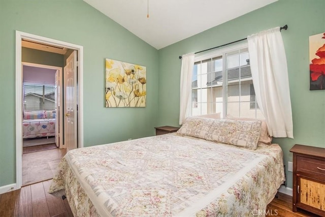 bedroom featuring lofted ceiling, baseboards, and wood finished floors