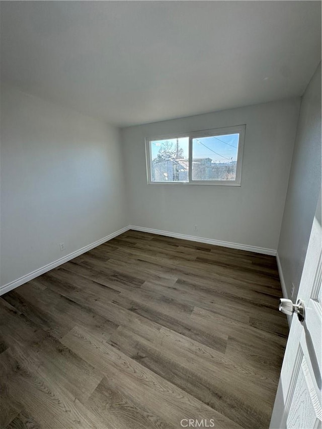 spare room with dark wood finished floors and baseboards