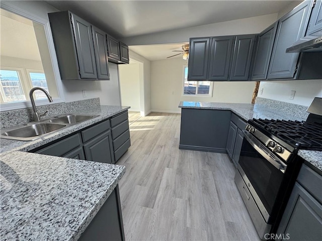 13063 Gilbert St, Edwards, CA 93523 - kitchen featuring stainless steel range with gas cooktop, ceiling fan, light wood-style floors, light stone counters, and gray cabinetry