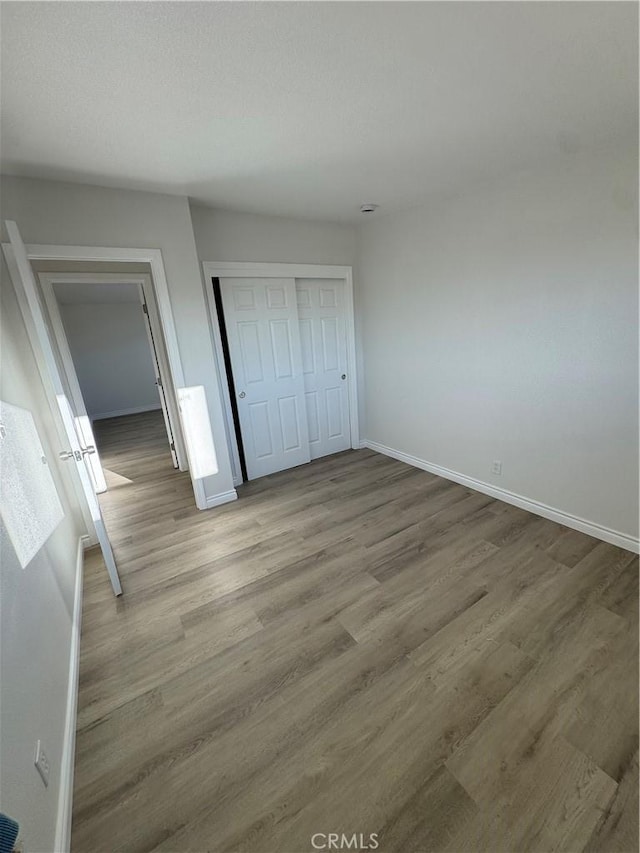 unfurnished bedroom featuring a closet, baseboards, and wood finished floors