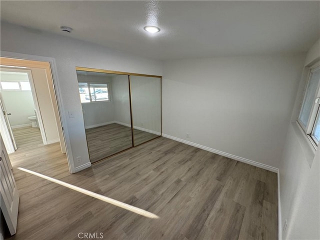 unfurnished bedroom with a closet, baseboards, and wood finished floors