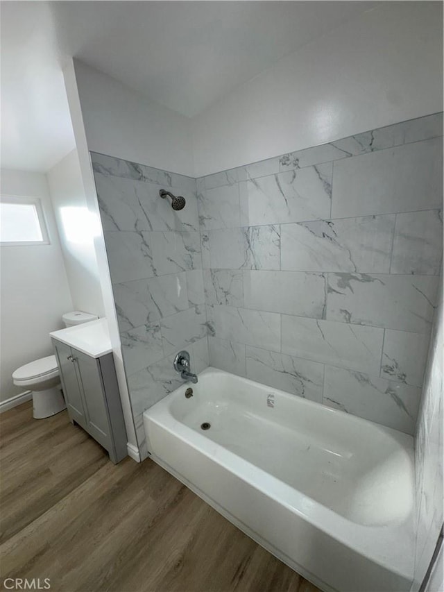 full bath featuring baseboards, toilet, shower / tub combination, wood finished floors, and vanity