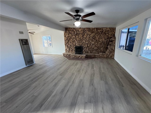 unfurnished living room with wood finished floors, a ceiling fan, visible vents, vaulted ceiling, and baseboards