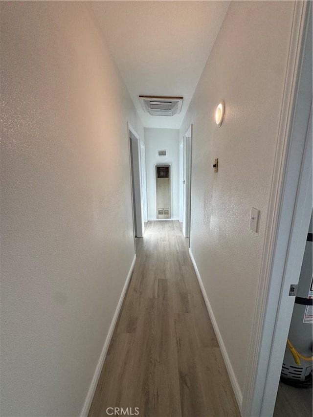 hallway featuring baseboards, visible vents, and wood finished floors