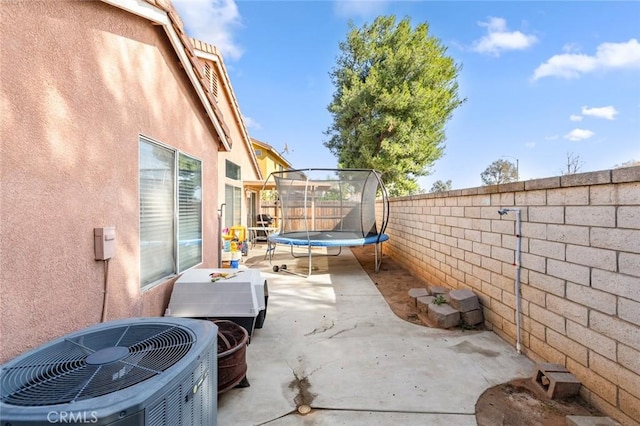 view of patio featuring a fenced backyard, a trampoline, and central AC unit