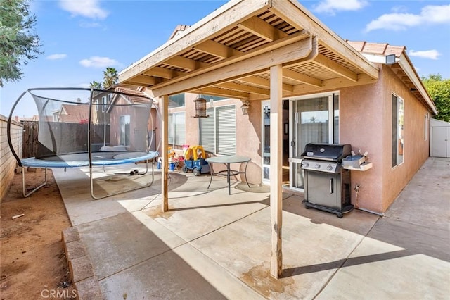 view of patio featuring a trampoline, a fenced backyard, and a grill