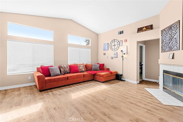 living area with baseboards, high vaulted ceiling, a fireplace, and light wood-style floors