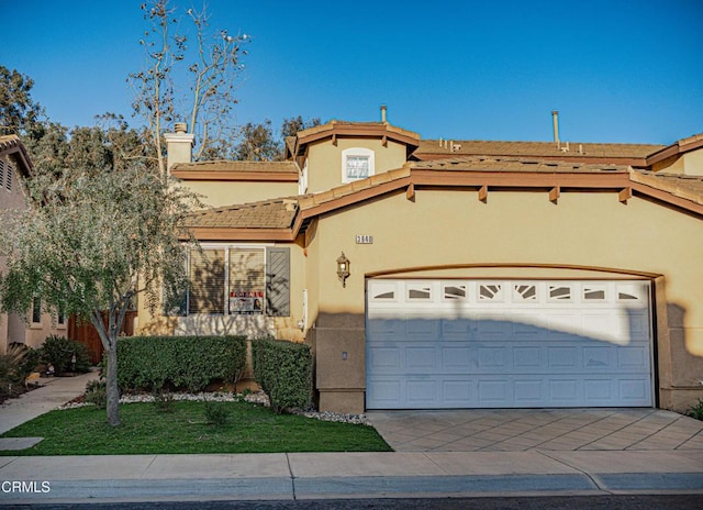 view of front of property featuring an attached garage, a tile roof, concrete driveway, and stucco siding