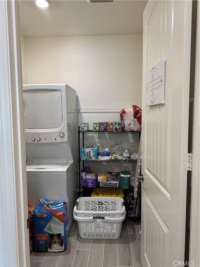 laundry area featuring laundry area, wood tiled floor, and stacked washing maching and dryer