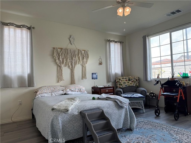 bedroom with ceiling fan, visible vents, baseboards, and wood finished floors