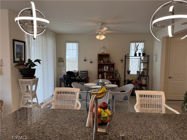 dining space featuring ceiling fan with notable chandelier