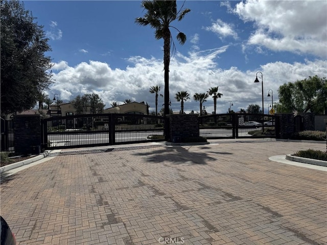 view of road featuring street lights, a gate, curbs, and a gated entry