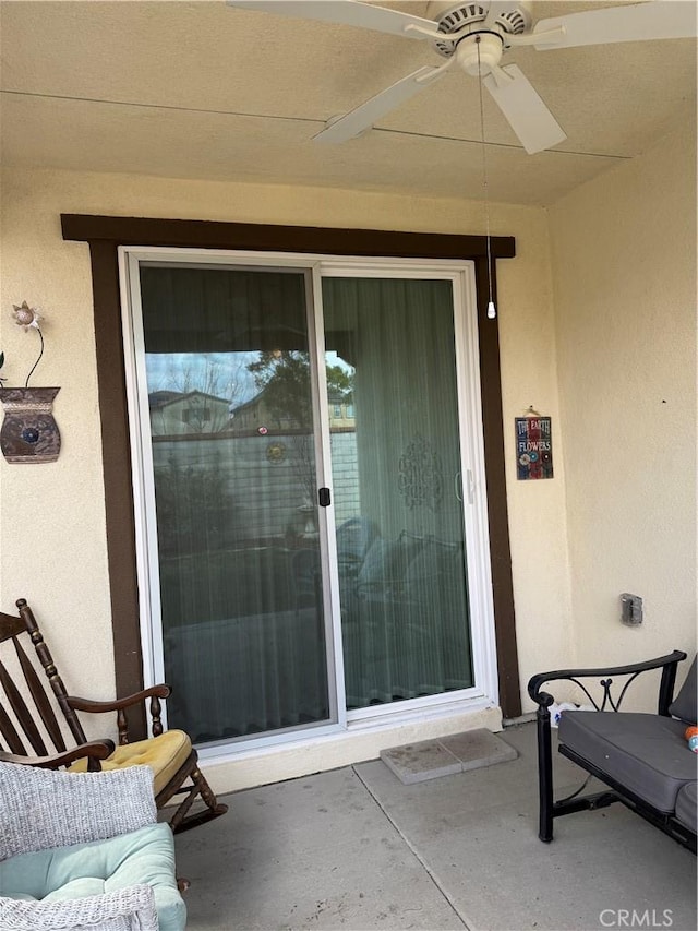 view of exterior entry featuring a ceiling fan and stucco siding