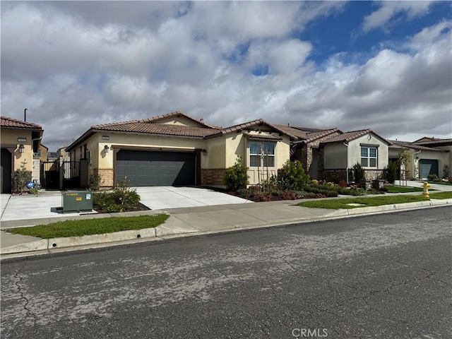 mediterranean / spanish house with stucco siding, a tile roof, a gate, concrete driveway, and an attached garage