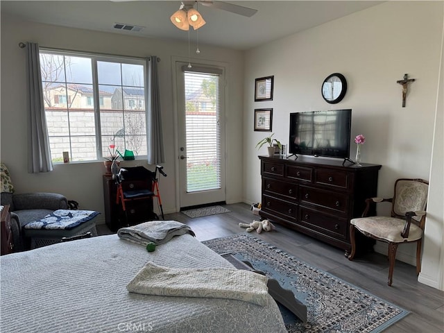 bedroom with wood finished floors, visible vents, baseboards, ceiling fan, and access to exterior