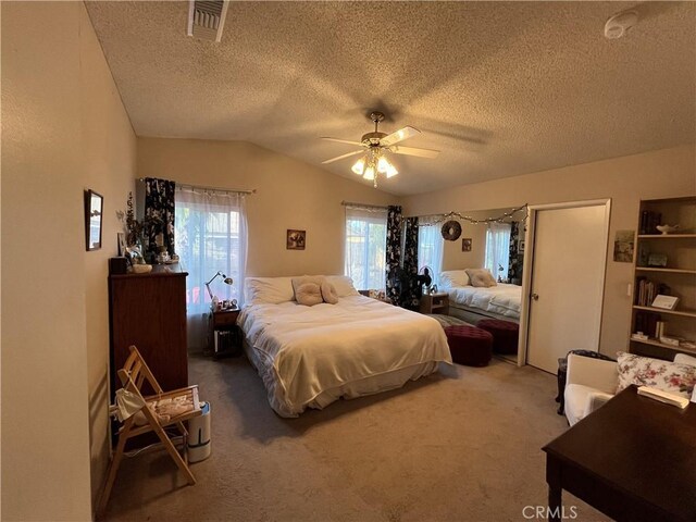 bedroom with vaulted ceiling, carpet flooring, visible vents, and a textured ceiling