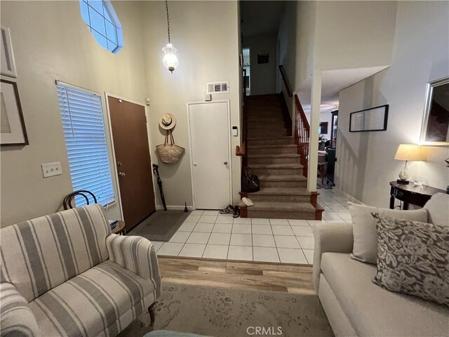 living area with stairs, wood finished floors, visible vents, and a towering ceiling