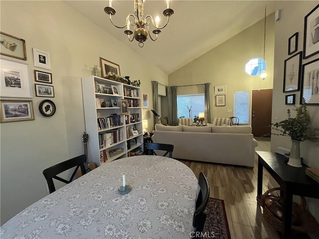 dining area with high vaulted ceiling, an inviting chandelier, and wood finished floors