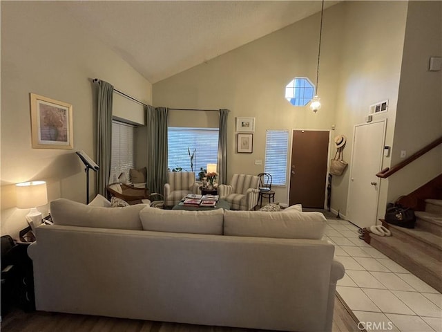 living room featuring stairs, light tile patterned floors, visible vents, and high vaulted ceiling