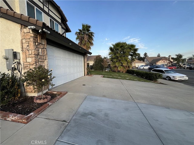 view of home's exterior with stucco siding, stone siding, an attached garage, and a tile roof