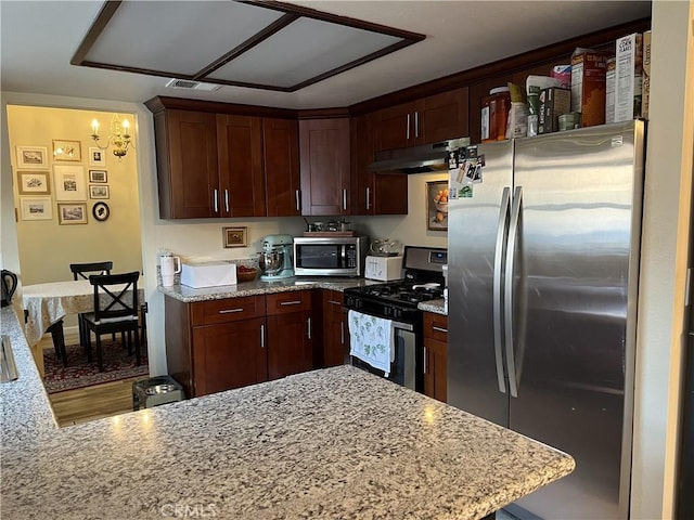 kitchen featuring under cabinet range hood, light stone countertops, visible vents, and appliances with stainless steel finishes