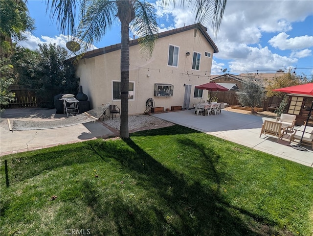 back of house with stucco siding, a yard, and fence